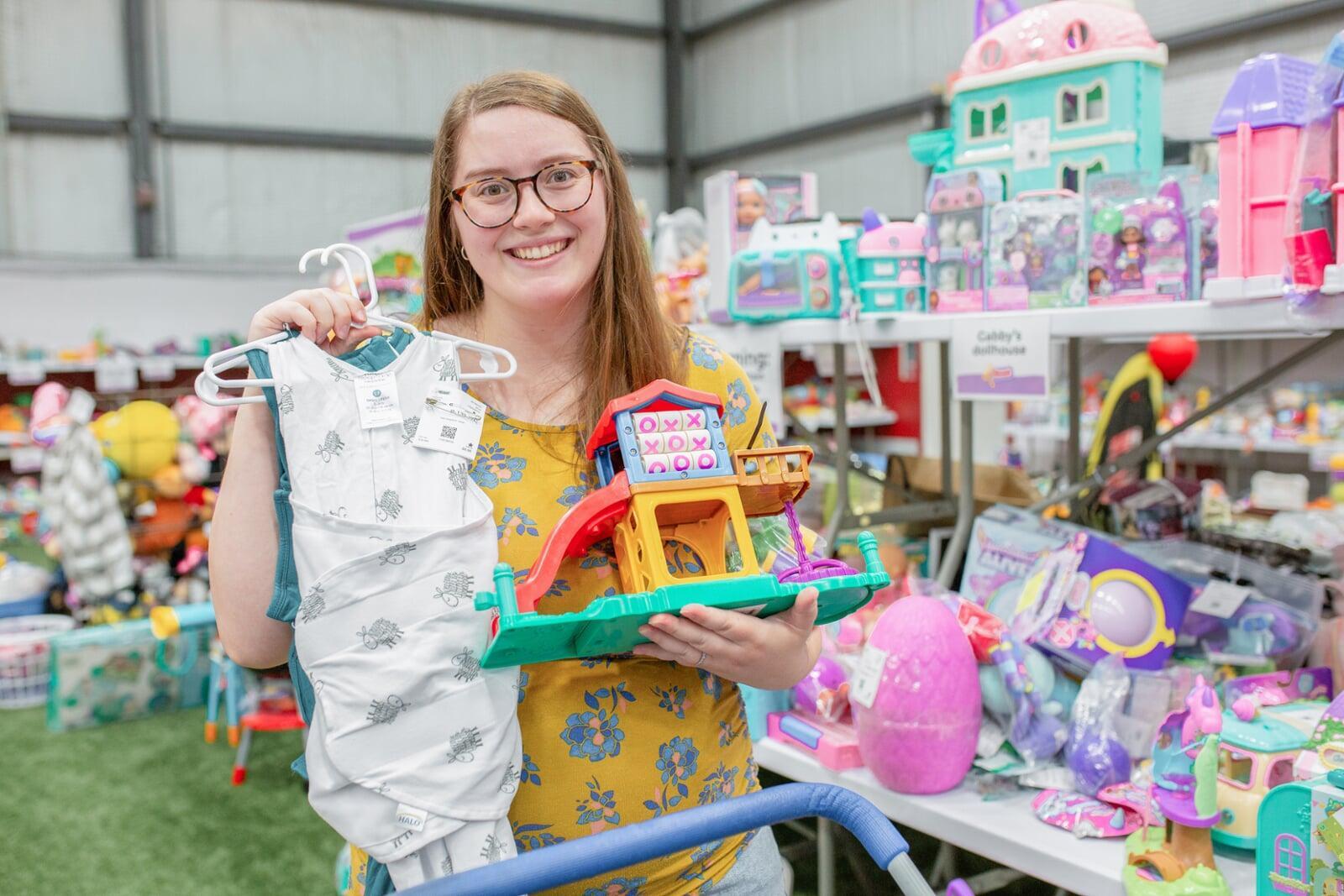 A JBF shopper mom in a black Metallica T-shirt holds an outfit she intends to buy at the JBF sale.