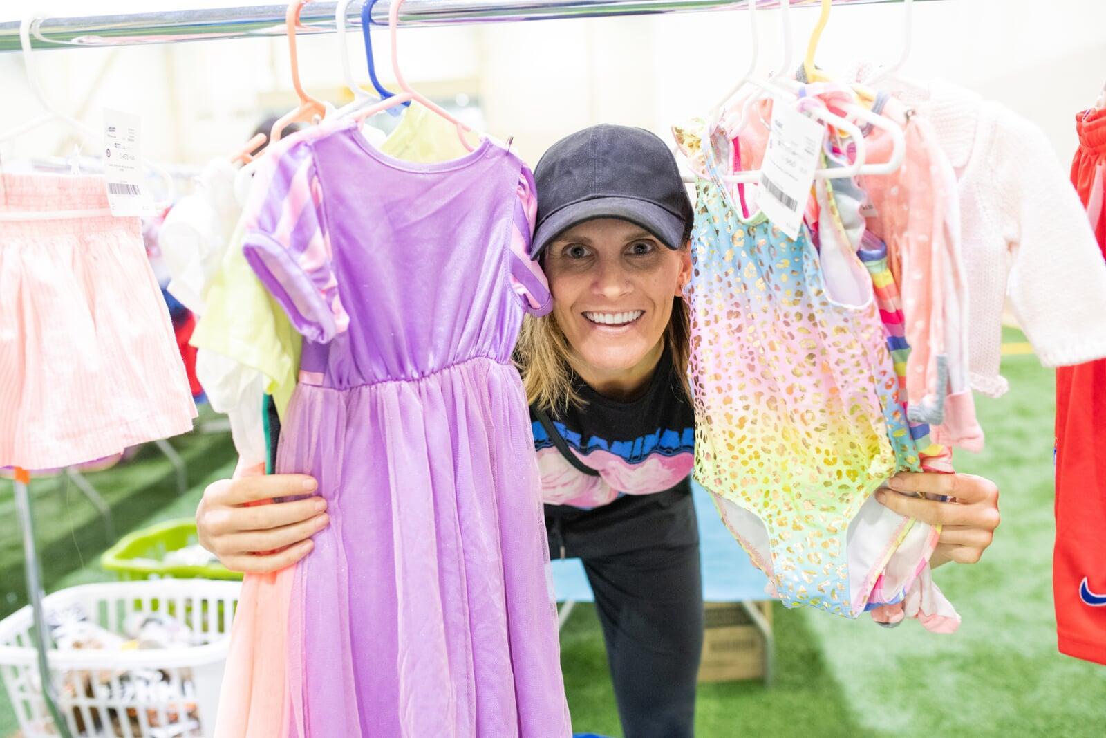 A mom and dad shopping at the JBF sale. Mom is holding a purple JBF shopping bag and dad carries his daughter in a front-pack carrier.