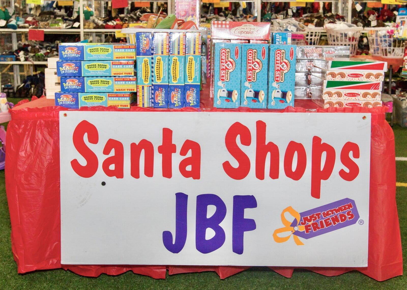 Toys displayed on a table that says "Santa Shops JBF".