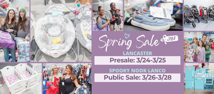 Two ladies smile as the hold up hangers with clothing on them. They are both standing next to a rack full of clothing for sale.