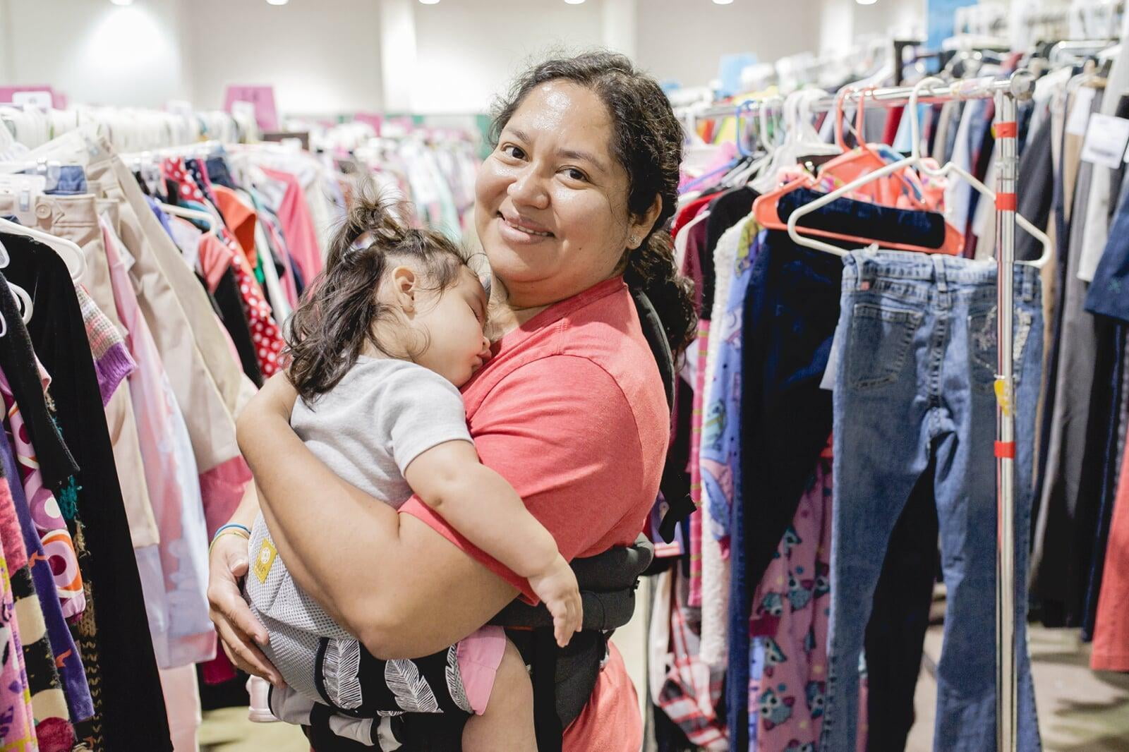 Mom holds daughter who is sleeping in her arms while she shops the JBF sale.