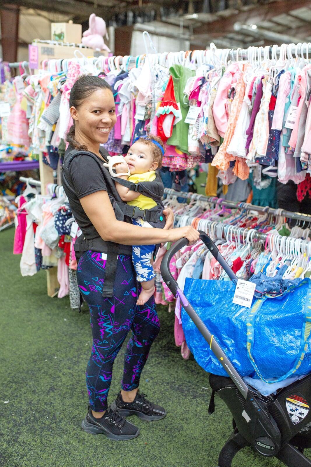Two friends shop together—one mom wears her baby girl—as they find great deals at the JBF sale.